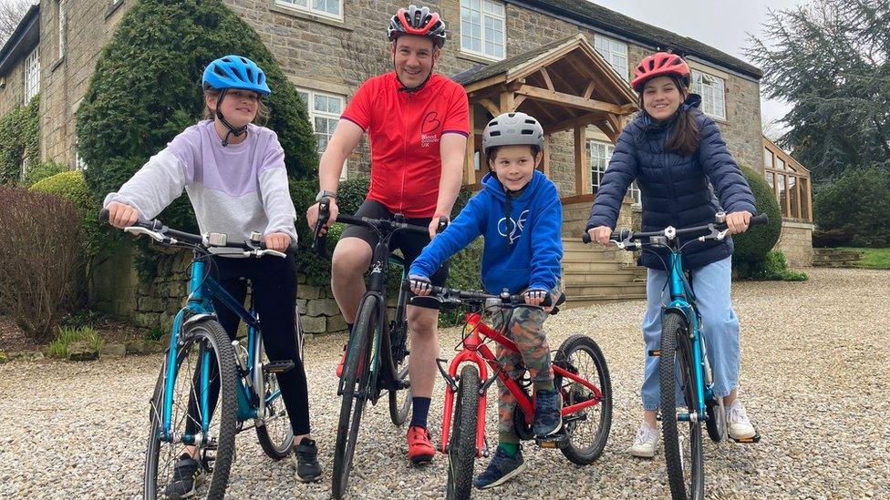 Man with three children on bicycles