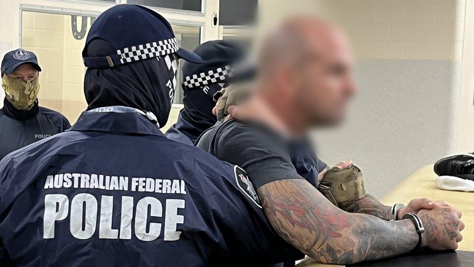 A handcuffed man whose face is blurred pictured beside police officers