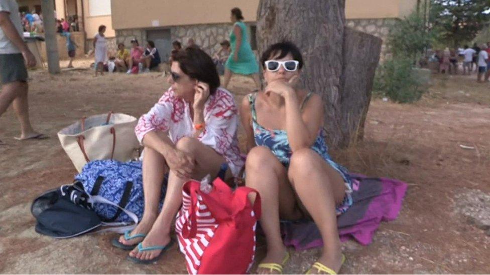 A still from EVN footage shows two women in holiday clothes sitting on the floor in Calampiso, which was evacuated on 12 July 2017