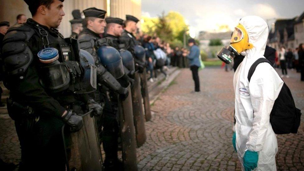 A man wearing a protective suit faces anti-riot police as residents protest during a demonstration called by unions and ecology activists to denounce the owners of the Lubrizol factory and the authorities suspected of "hiding the truth", 1 October 2019