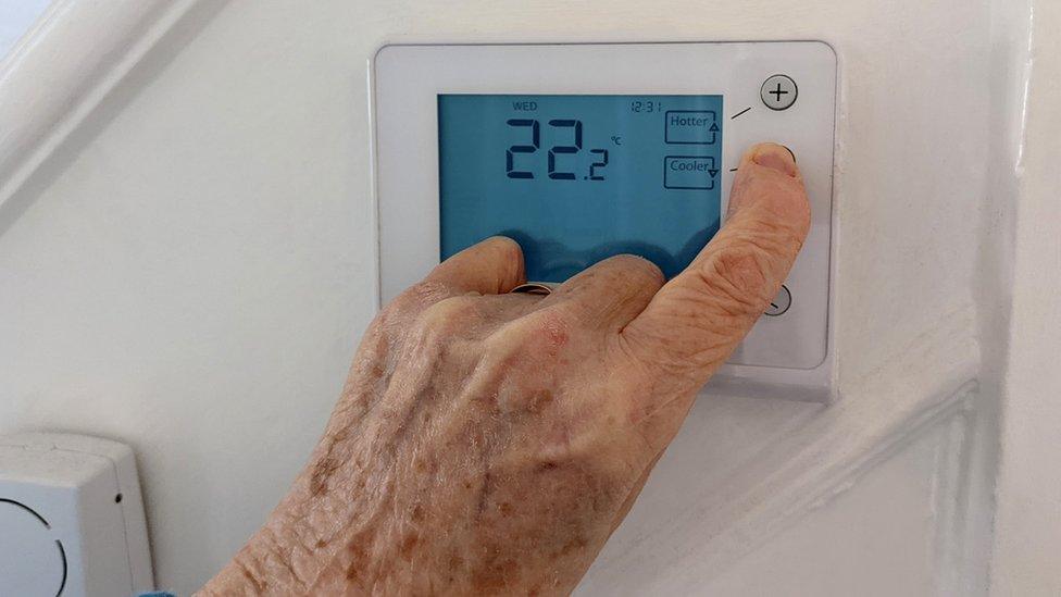 Person yn defnyddio thermostat