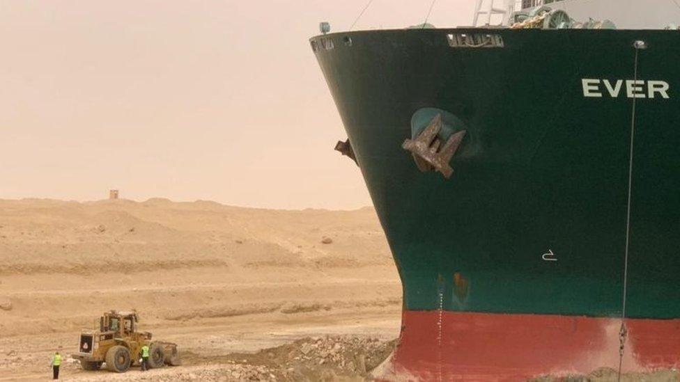 Workers are seen next to a container ship which was hit by strong wind and ran aground in Suez Canal, Egypt 24 March 2021.