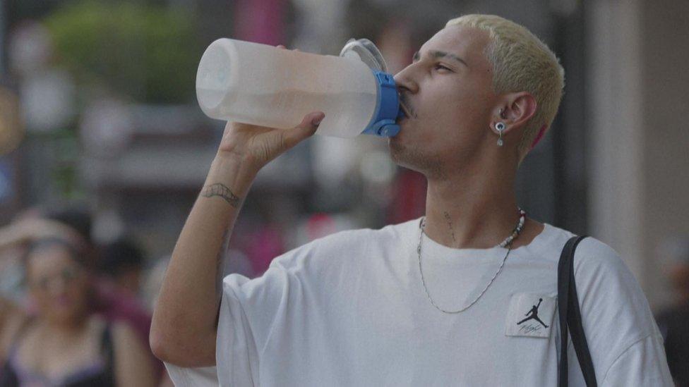 A man drinks water on the street in Sao Paulo