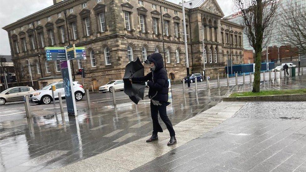 A woman struggles with her umbrella in Belfast, 16 February 2022