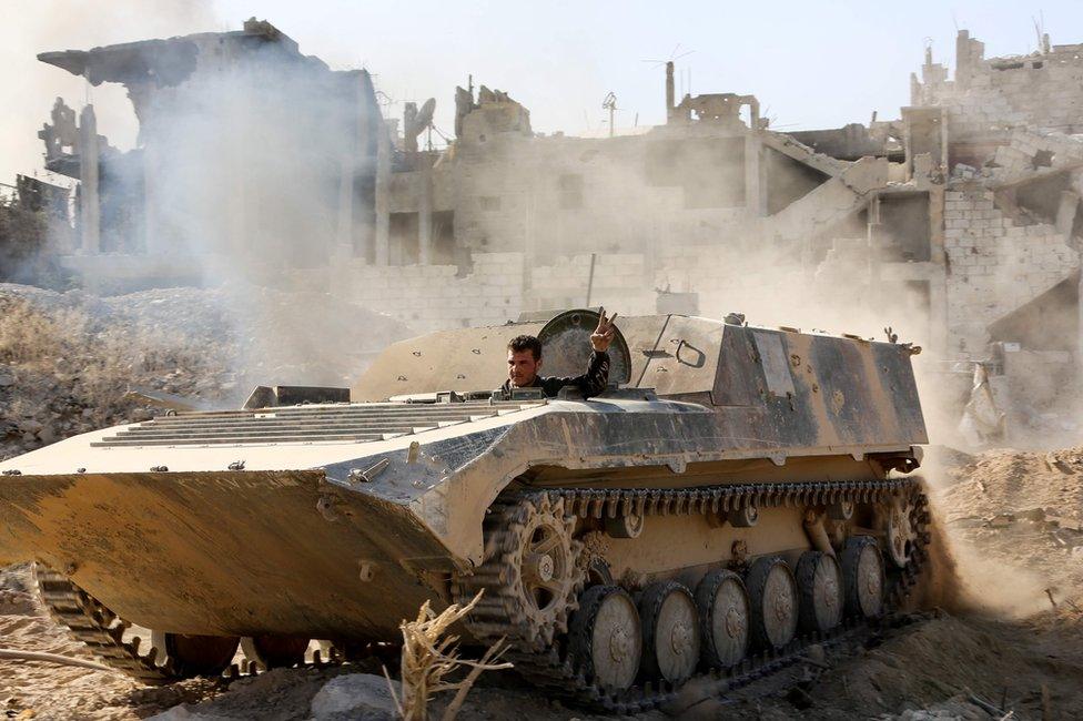 Syrian pro-government forces drive an armoured vehicle as they advance through the Qaboun district of Damascus on 13 May 2017