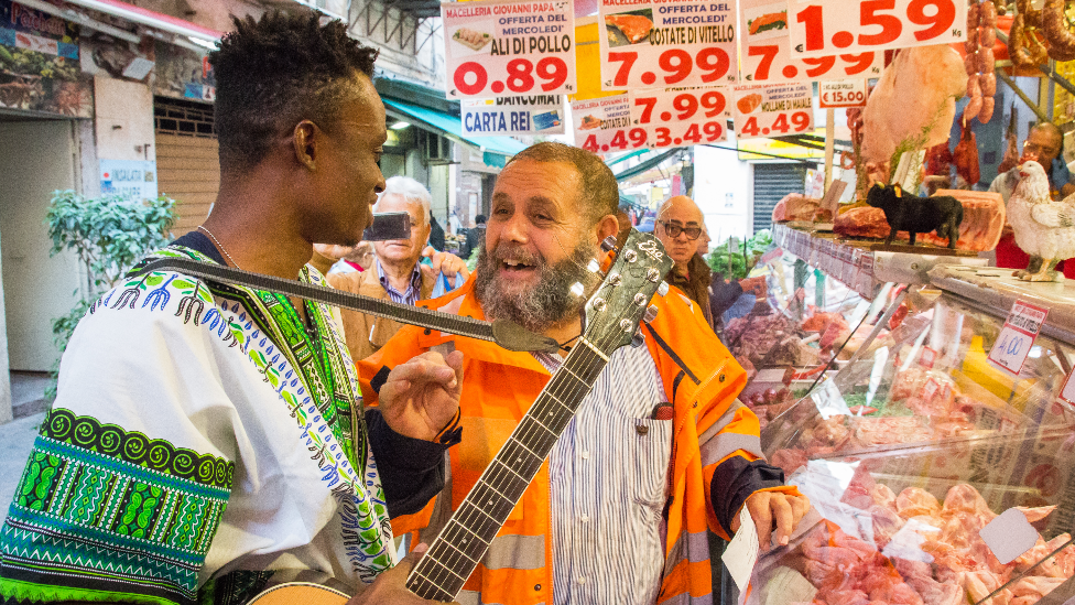 Singer Chris Obehi being created by Sicilians at a butcher's shop in Sicily