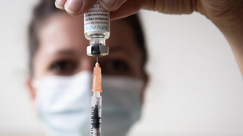 A nurse draws down on a syringe inserted into a monkeypox vaccine vial