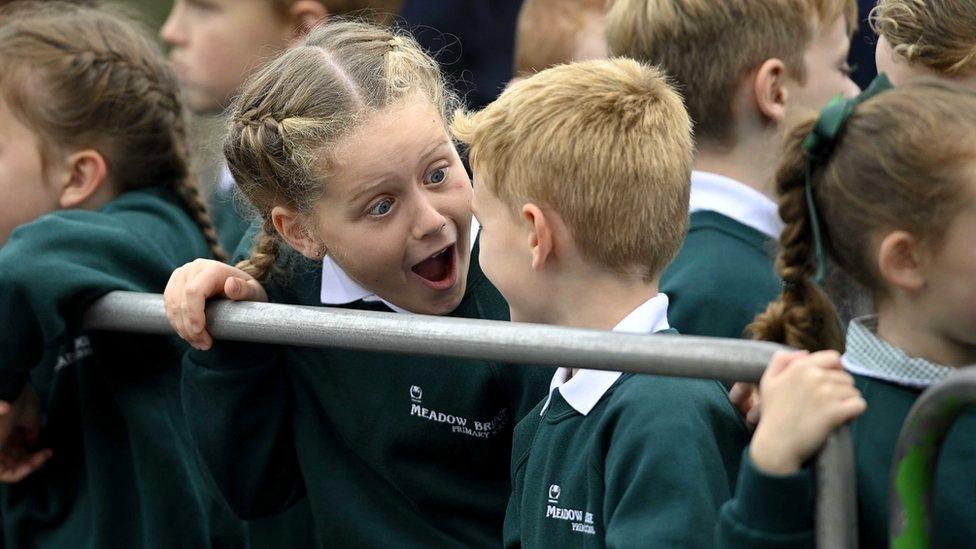 Two excited schoolchildren speak to each other after meeting the King and Camilla outside Hillsborough Castle