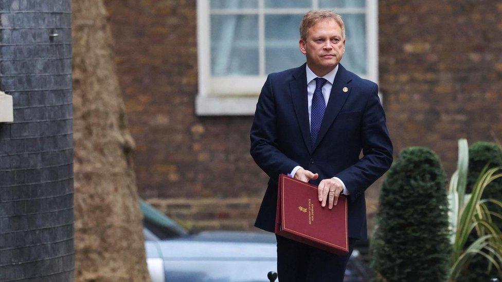 Defence Secretary Grant Shapps seen walking along Downing Street. He is wearing a blue suit and tie and holding a red binder