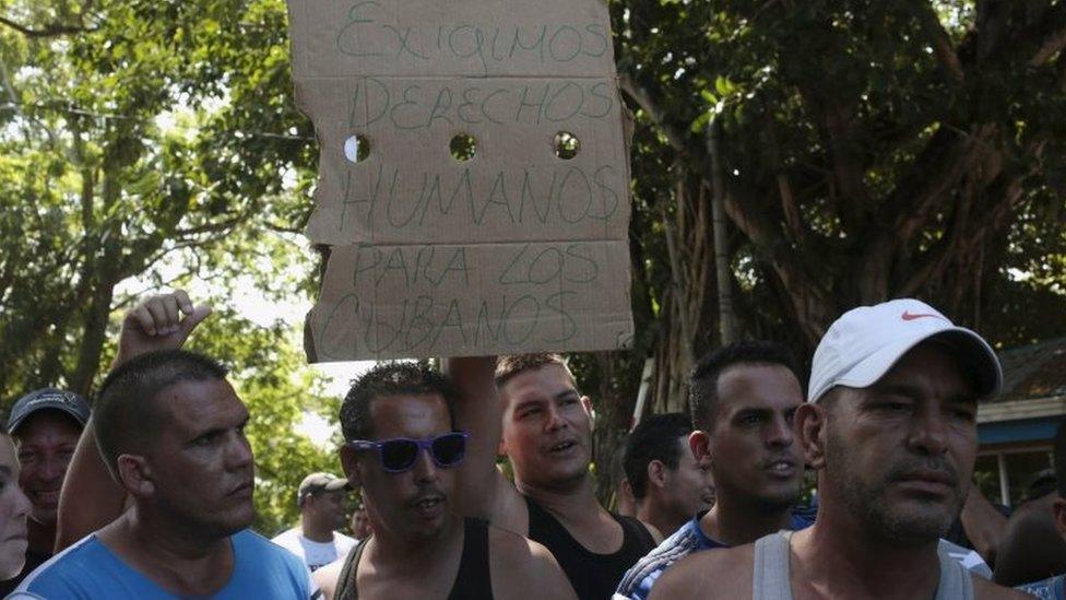 A Cuban migrant holds a sign that reads "We demand human rights for Cubans" at the border between Costa Rica and Nicaragua in Penas Blancas on 17 November, 2015.