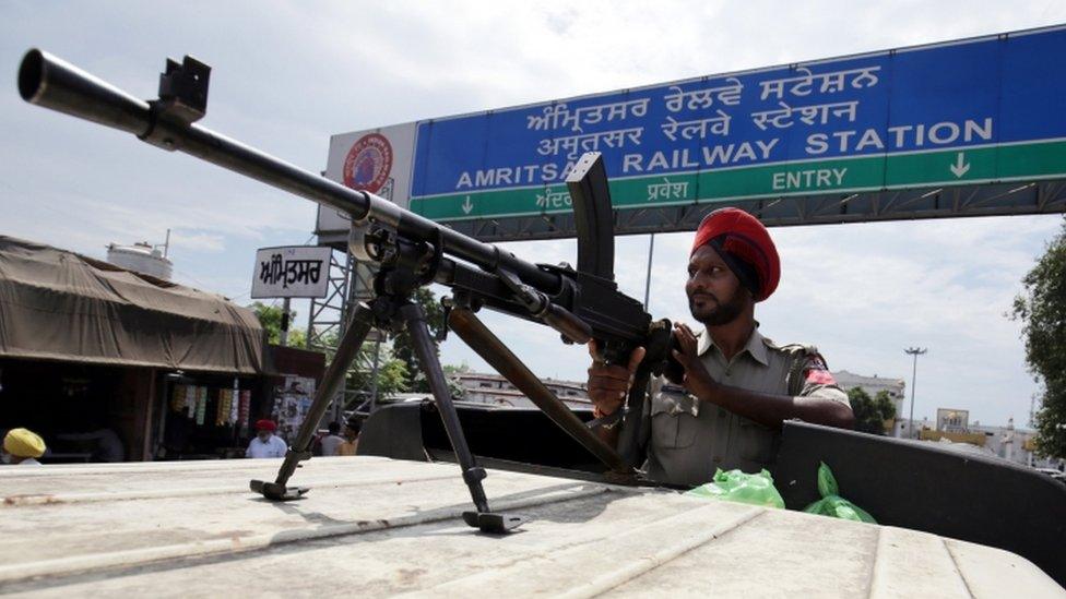 A Punjab policeman stands guard with a gun outside the railway station as trains are cancelled in Amritsar, India, on 26 August 2017.