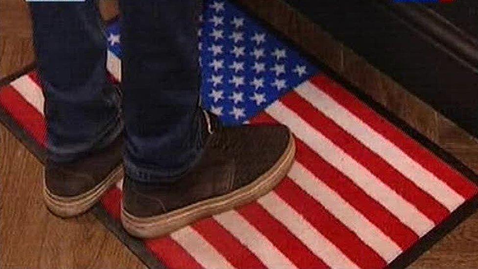 A visitor's feet on the US flag doormat