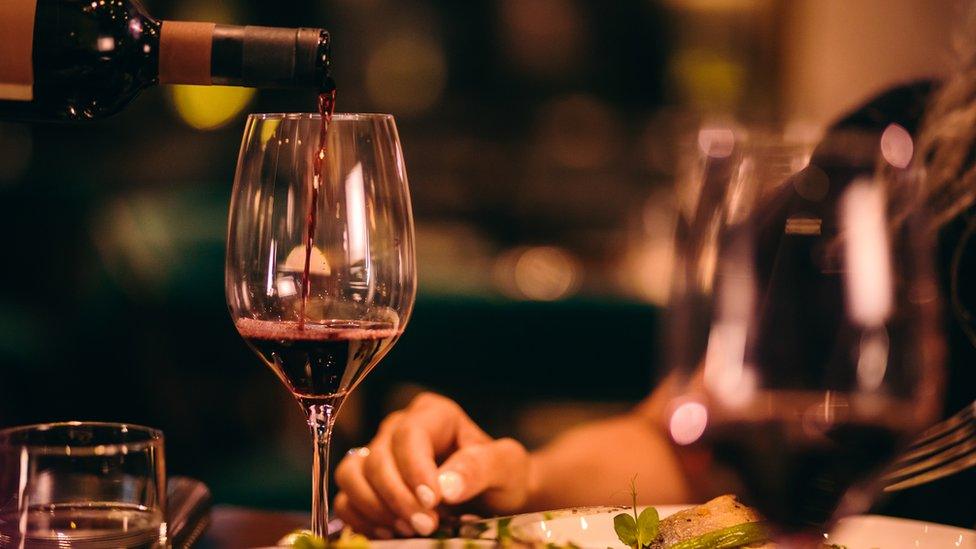 Red wine being poured into a glass at dinner table