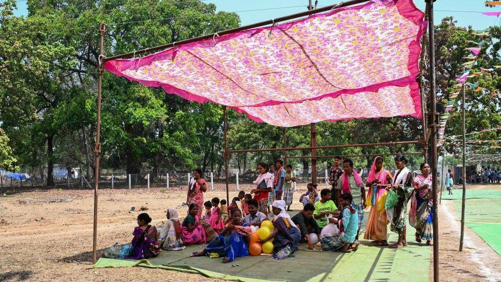 Voters take shelter from the sun outside a polling station to cast their ballot on a hot day during the first phase of voting of India's general election, in Dugeli village some 33 Km (21 miles) from Dantewada town in Chhattisgarh state on April 19, 2024. As the world's biggest democracy began a six-week election on April 19, thousands of people in villages across Bastar district, one of the last strongholds of the Naxal rebels, cast their ballots. (Photo by Idrees MOHAMMED / AFP) / TO GO WITH 'India-vote-conflict-Maoist', FOCUS by Bhuvan Bagga (Photo by IDREES MOHAMMED/AFP via Getty Images)