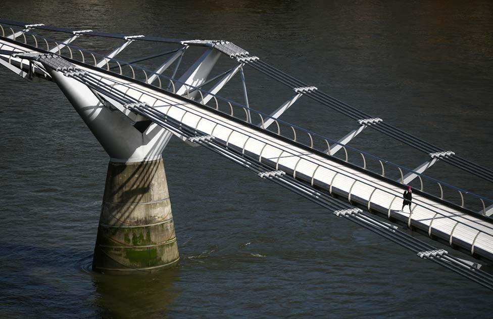 A woman walks across an empty Millennium Bridge during rush hour