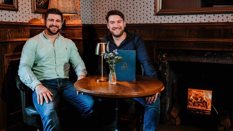 Two men sat at a table smiling