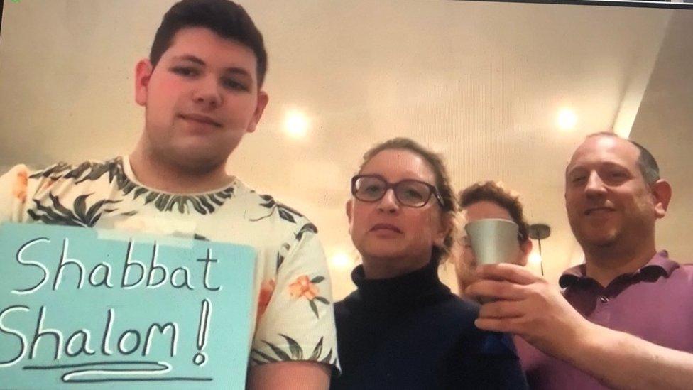 Family holding a sign reading Shabbat Shalom