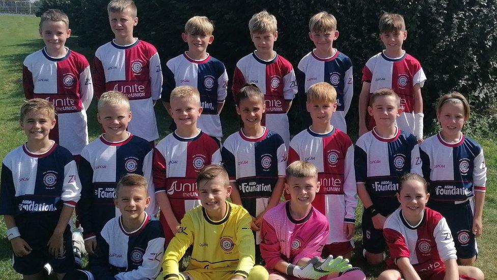 Children smiling as they pose for their football team photo