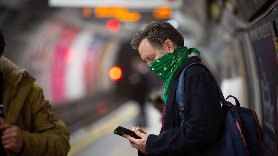 Commuter on the London Underground, checking his mobile phone