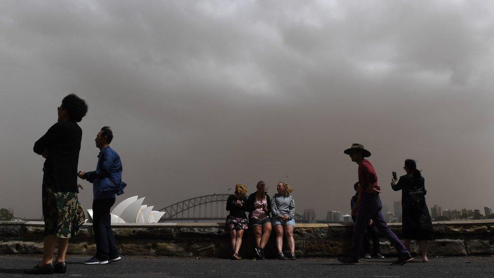 Tourists in Sydney framed against a thick dust-filled sky