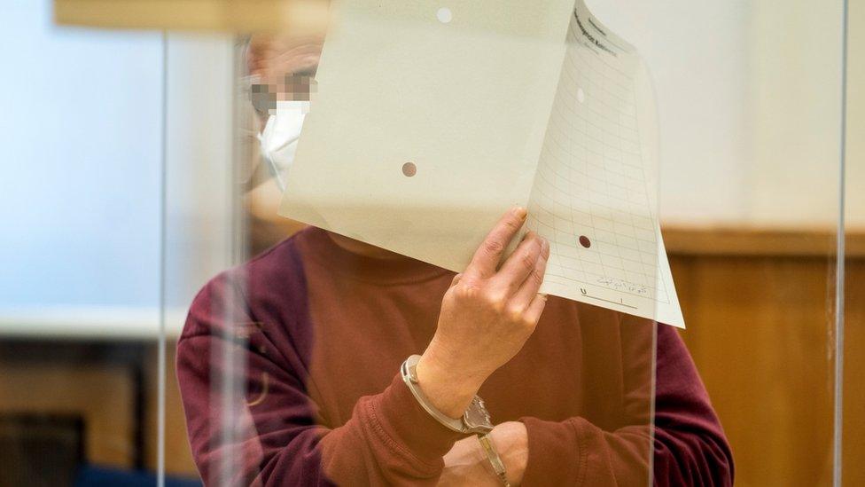 Former Syrian intelligence officer Eyad al-Gharib holds up a file in court in Koblenz, Germany (24 February 2021)