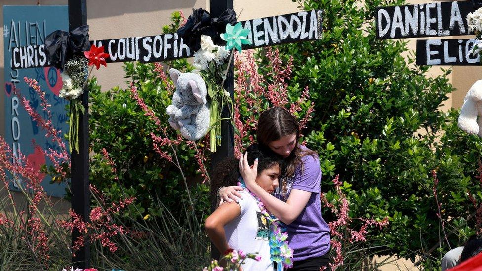 Mourners visit a memorial set up near the scene of the Allen mall shooting