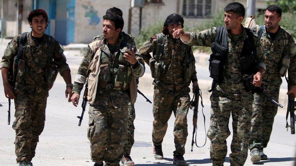 Kurdish fighters from the People's Protection Units (YPG) walk along a street in the southeast of Qamishli city, Syria (22 April 2016)