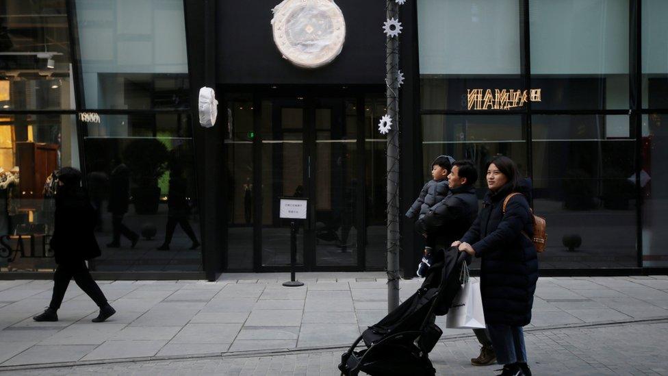 A family walk past a closed Canada Goose store in Beijing.