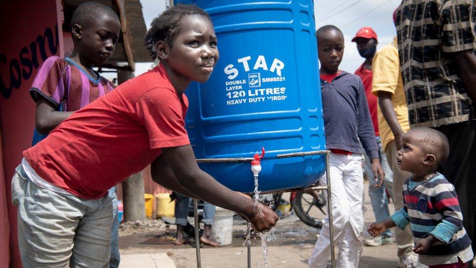 Kids in Mathare help each other to wash hands at a hand washing station on July 6, 2020 in Nairobi, Kenya