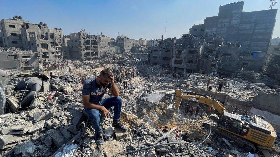 A man sits atop a pile of rubble following an Israeli strike on the Gaza Strip