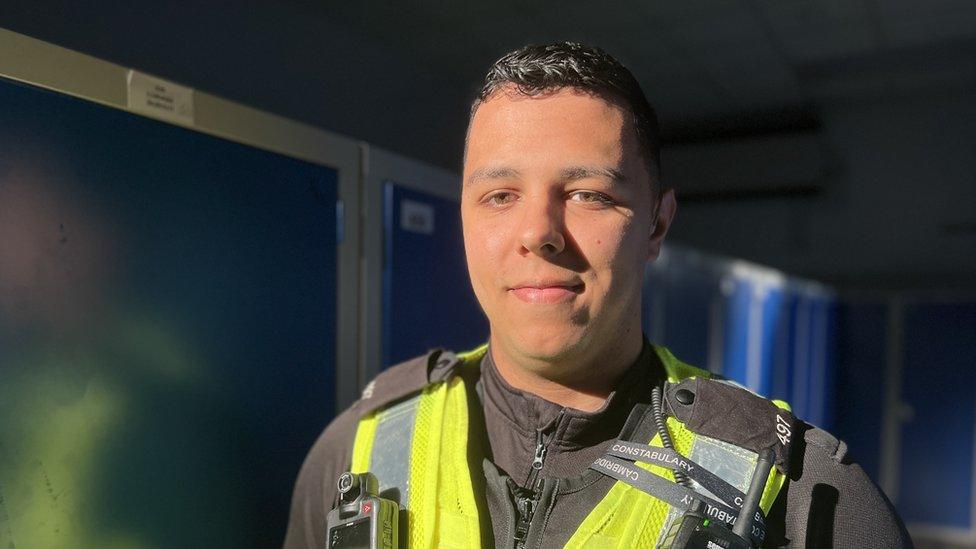 Police officer in uniform in front of some lockers