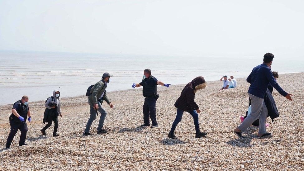 People being directed up a beach by Border Patrol