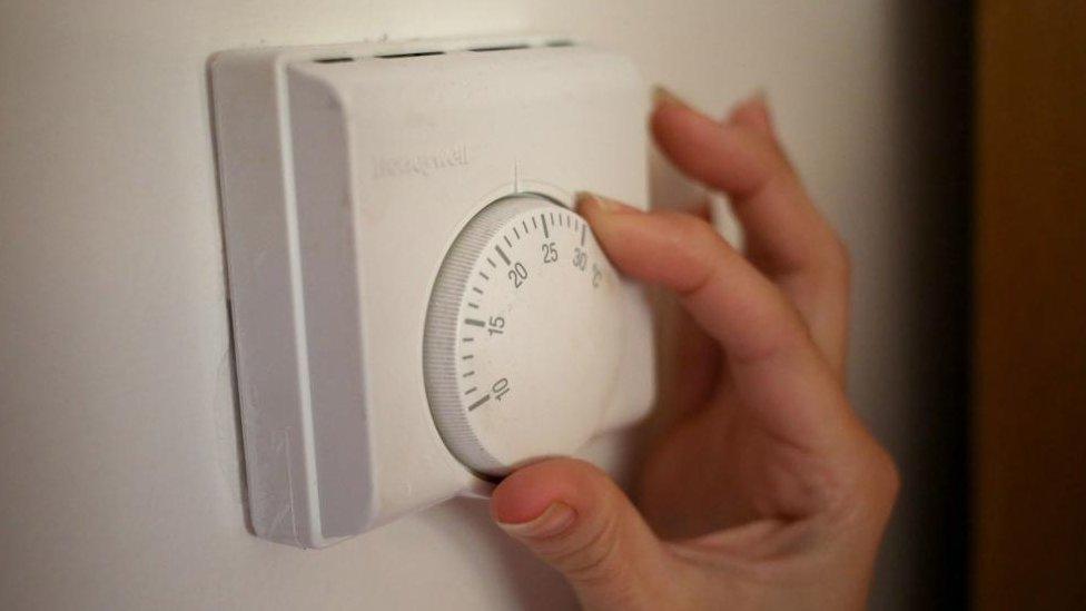 A person using a central heating thermostat