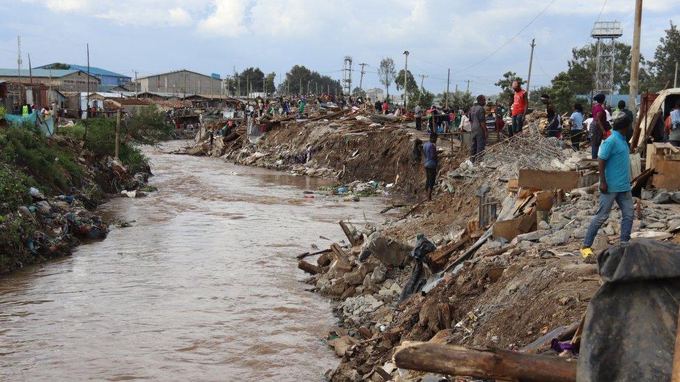 River running through slum area with demolished houses nearby