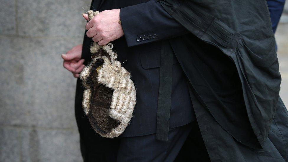 A barrister holding a wig