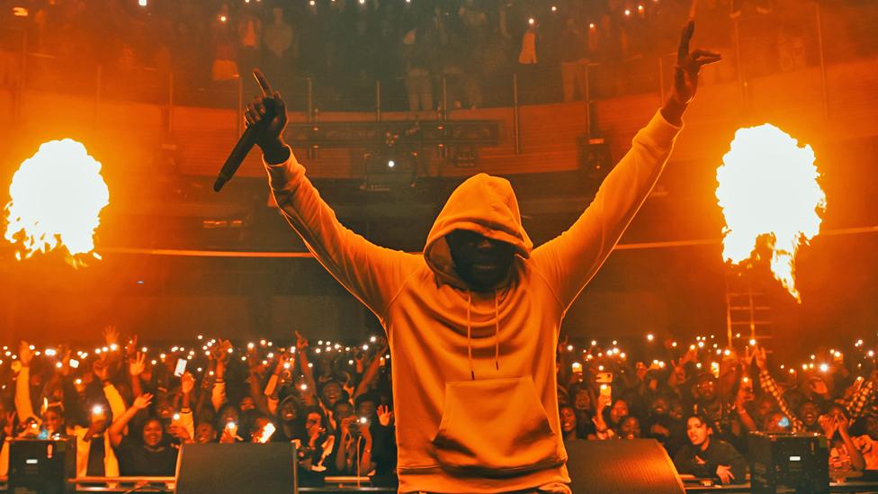 Medikal with hands aloft in concert at O2's Indigo venue in London, the UK