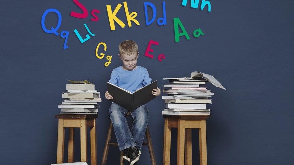 A boy surrounded by books reading