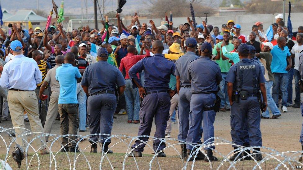 Police stand by as striking miners celebrate securing a 22% pay hike from London-listed Lonmin platinum mine in Marikana on September 18, 2012.