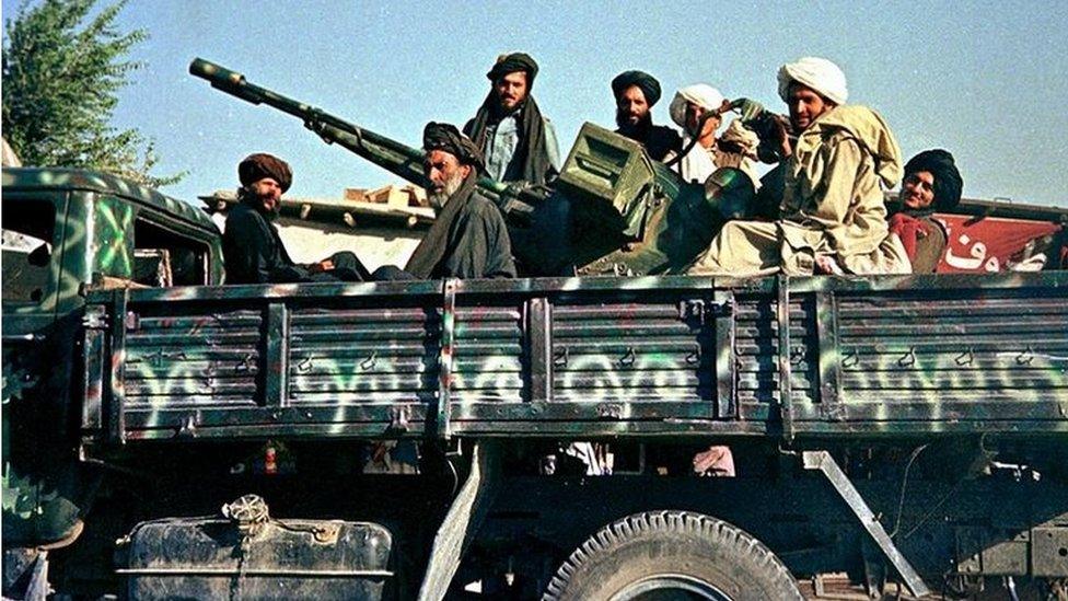 Afghan Taliban soldiers 28 July 2000 pose in Kabul on their newly-painted military truck with their anti-aircraft gun on the way to the frontlines north of the capital.