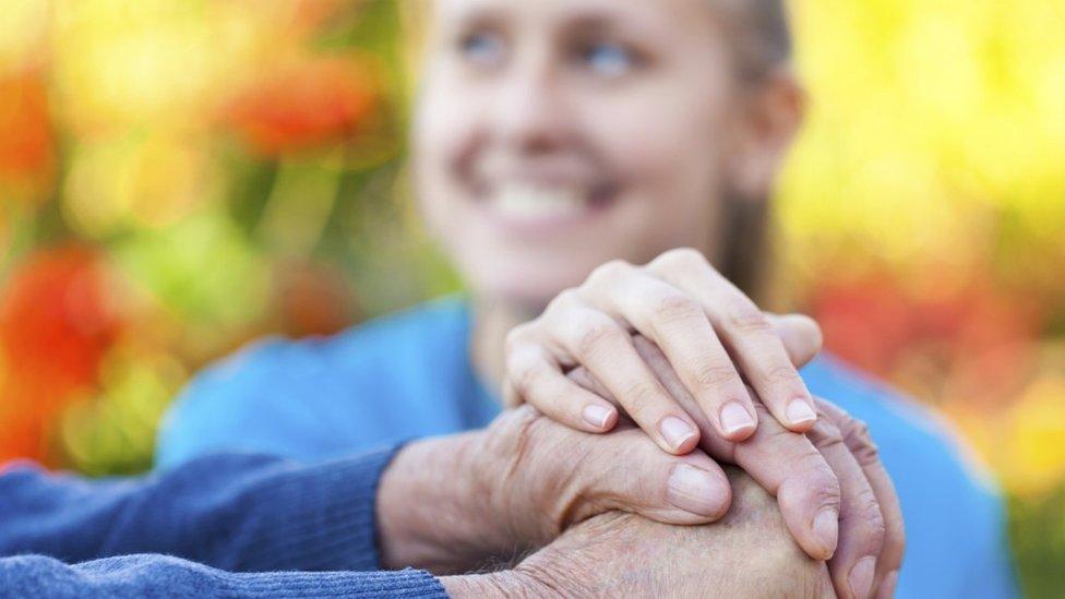 Woman holding older person's hand