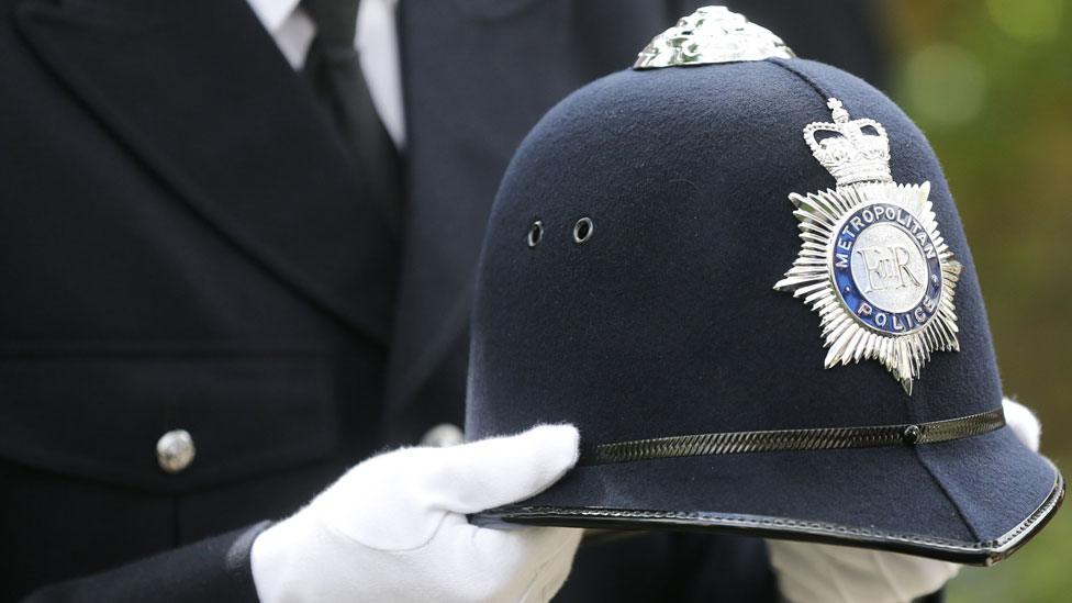 A police officer carrying PC Palmer's helmet