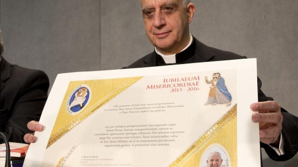 Archbishop Rino Fisichella holds up a certificate of participation, which will be given to faithful who will have made a pilgrimage by foot to the Vatican for the Jubilee Year of Mercy