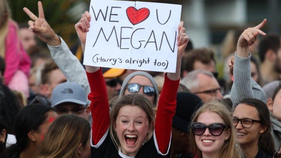 A fan with a "we love you Meghan" sign