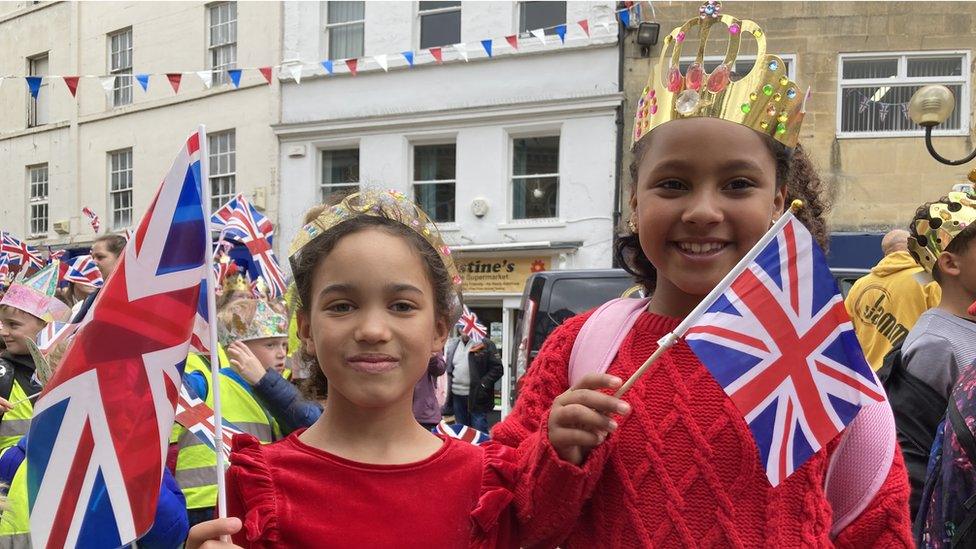 Two children wearing crowns and waving flags, dressed in red