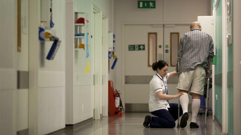 A nurse tending to a patient in a hospital