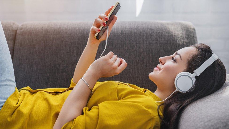 A woman listening to music using headphone (stock image)