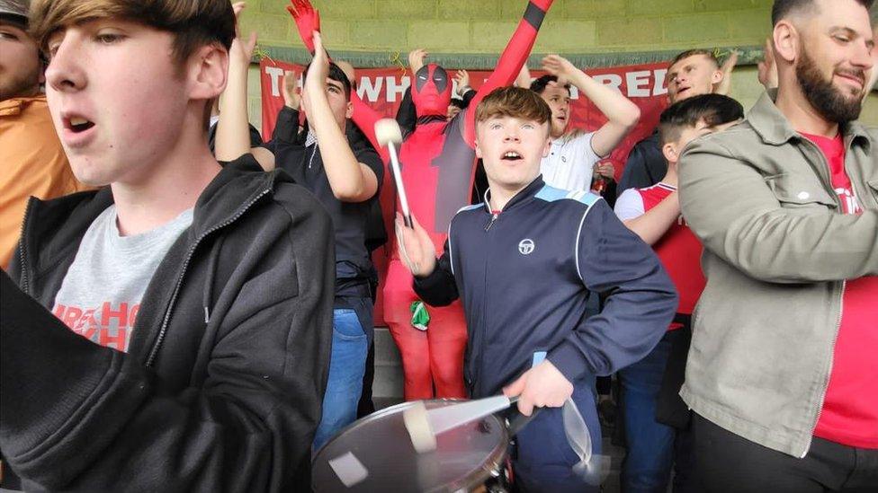 Mannie drumming in a crowd of supporters at Torquay during the last game of the season