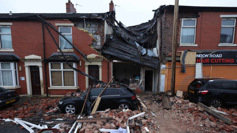 Debris litters the road and pavement after the explosion at the terraced house