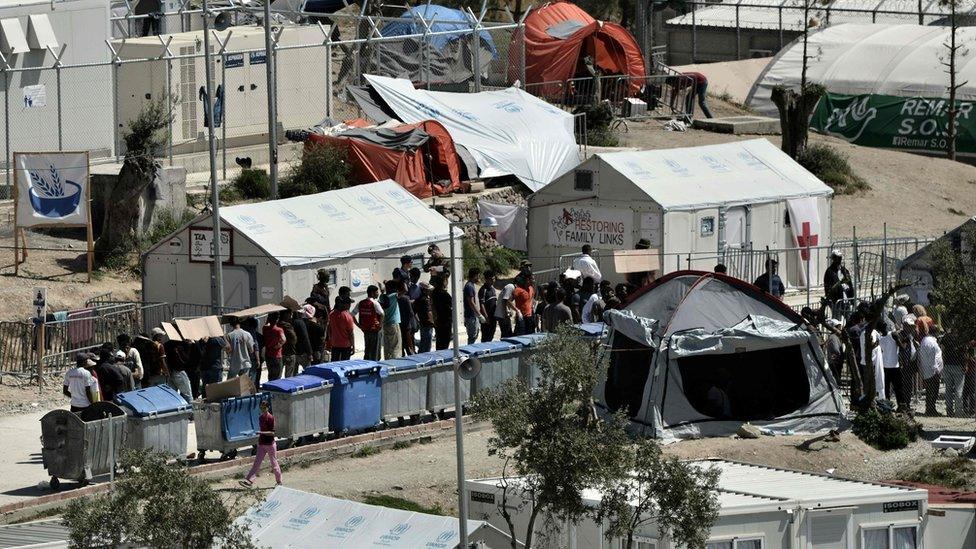 Refugees and migrants line up inside Moria detention center in Mytilene one day before the visit of Pope Francis on April 15, 2016