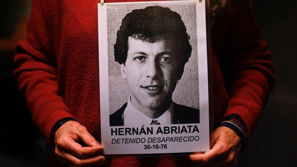 Monica Dittmar, the wife of missing Hernan Abriata, holds a picture of him as she waits for the beginning of the trial against Argentine former police officer Mario Sandoval over Abriata's disappearance at the federal courts in Buenos Aires, on September 14, 2022